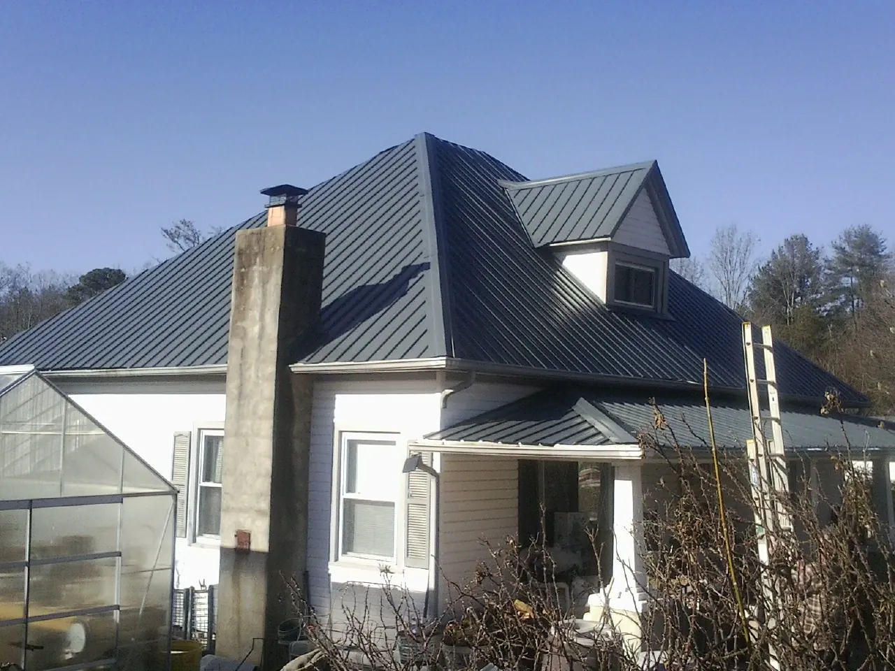 Dark blue standing seam metal roof on a white farmhouse with dormer — Slate & Tile Roof Repair by Roofing Brothers in Beaver Crossing