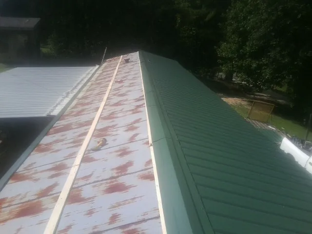 Old rusted panels beside newly installed green metal roofing — Wind Damage Roof Repair by Roofing Brothers in Beaver Crossing