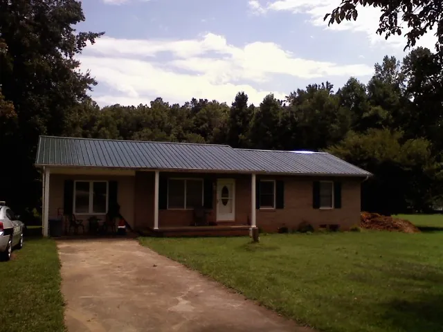 Dark green metal roof on a brick ranch with a covered porch in Beaver Crossing