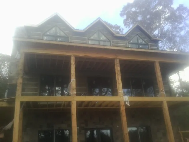 Dormers and porch framing on a large log home under construction — Roof Coating work by our crew in Beaver Crossing