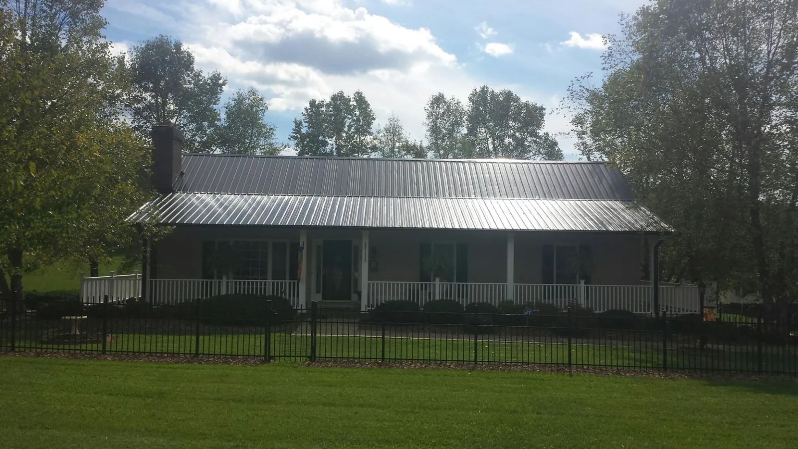 Gray metal roof on a brick ranch with a full width front porch — Gutter Guard Installation work by our crew in Beaver Crossing