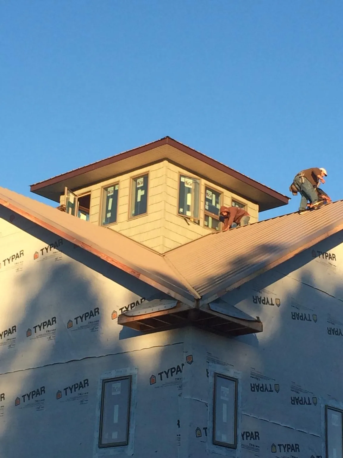 Roofers working around a rooftop cupola on a new metal roof at sunset — Roof Waterproofing in Beaver Crossing by Roofing Brothers